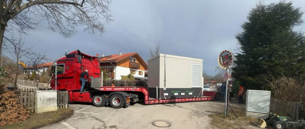 Großer roter Sattelzug, der fertiges Baumodul, den Point of Presence, einen sogenannten PoP geladen hat.