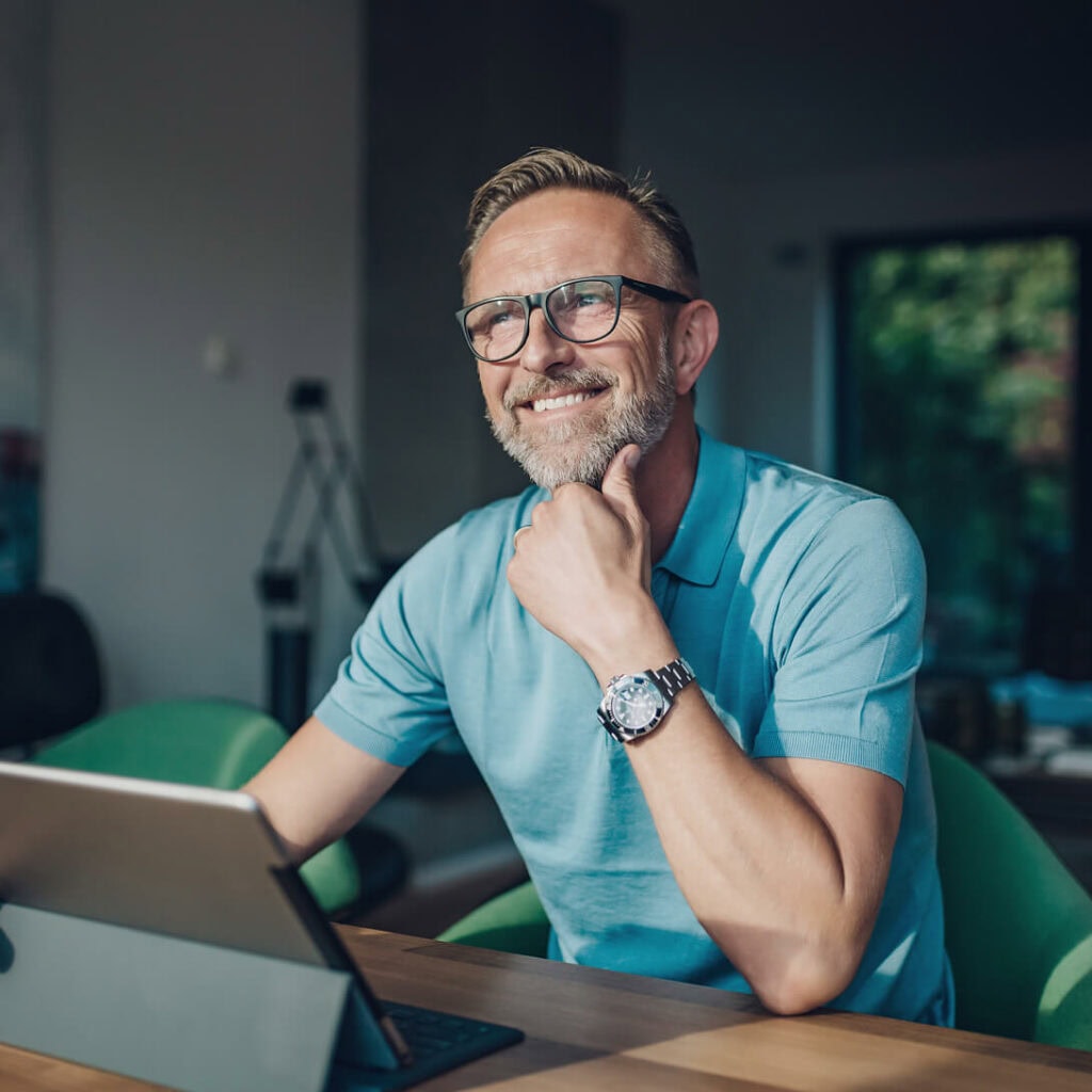 Zufriedener Kunde sitzt entspannt am Laptop in heller, moderner Umgebung – Szene einer Glasfasersprechstunde.