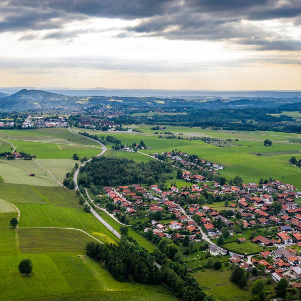 Luftaufnahme einer ländlichen Gemeinde in Oberbayern – modernes Glasfasernetz verbindet rote Ziegeldächer mitten im Grünen.