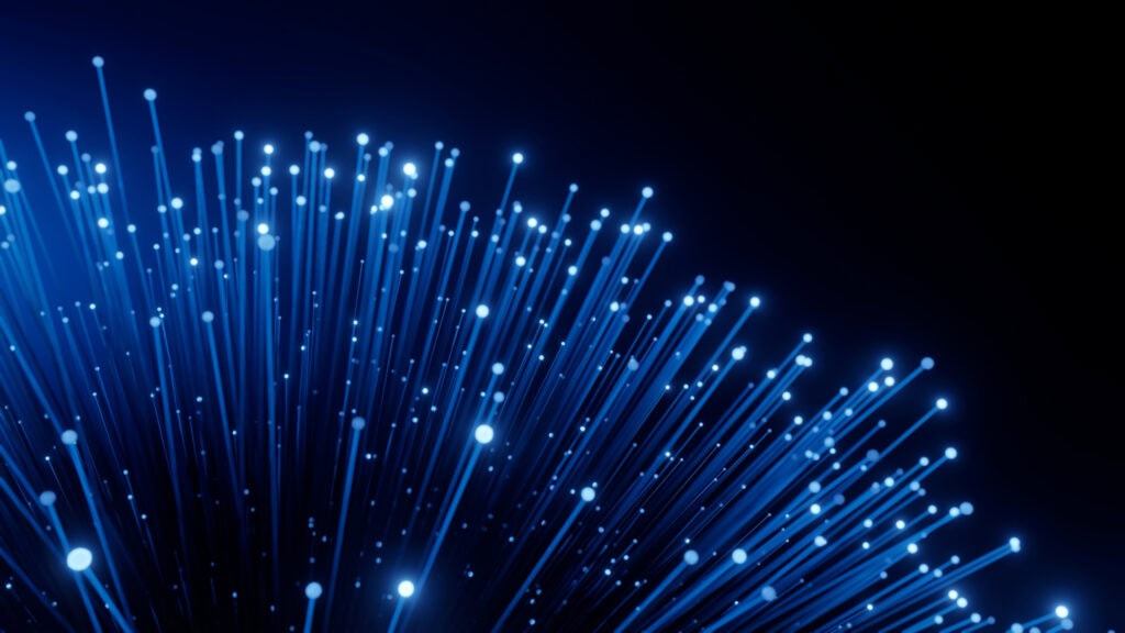 Leuchtende Glasfaserkabel in Nahaufnahme vor dunklem Hintergrund – Symbol für ultraschnelle Datenübertragung und moderne Breitbandtechnologie.