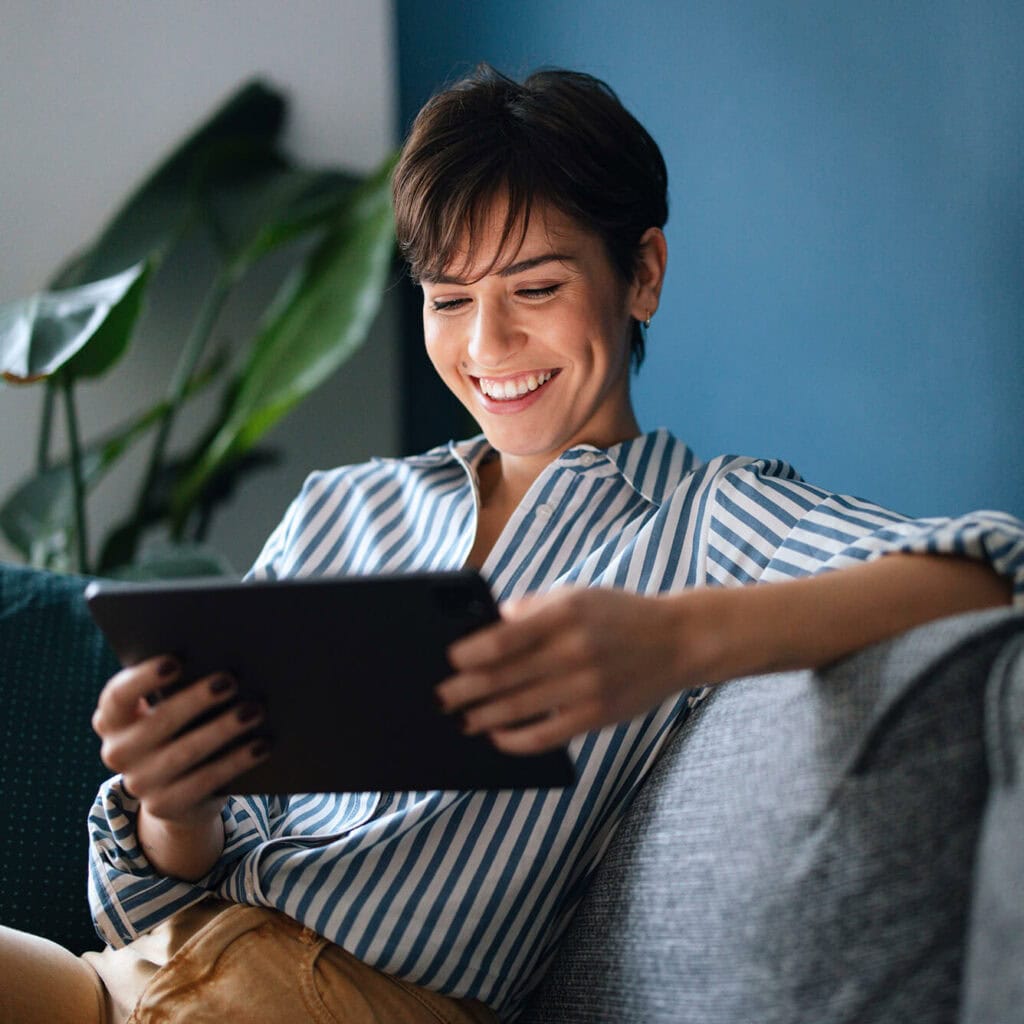 Frau mit Tablet auf Sofa – effizientes Immobilienmanagement durch stabile Glasfaserverbindung mit AVACOMM